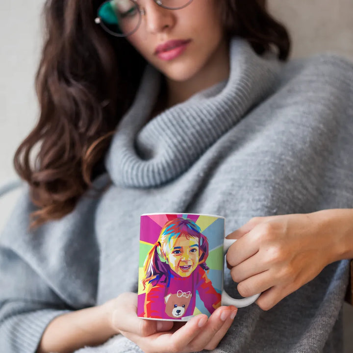 Person holding a mug with a colorful design of a child.