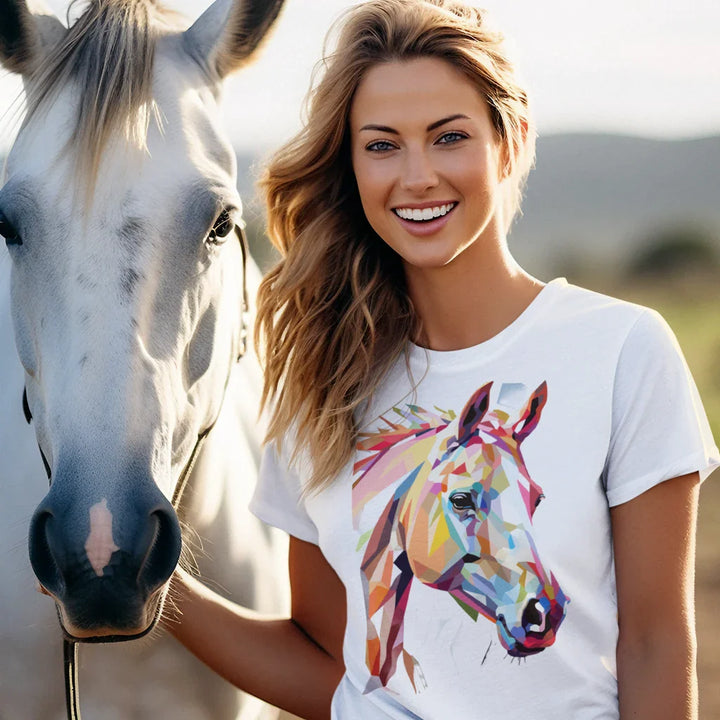 Woman wearing a white t-shirt with a colorful horse design, standing next to a white horse.